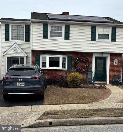 townhome / multi-family property with roof mounted solar panels and brick siding