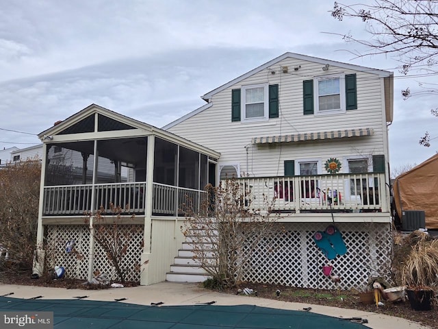 view of front of property featuring a sunroom, a covered pool, stairway, and central AC