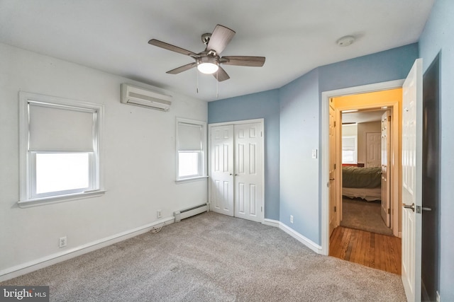 unfurnished bedroom featuring ceiling fan, a wall mounted AC, light carpet, a baseboard radiator, and a closet