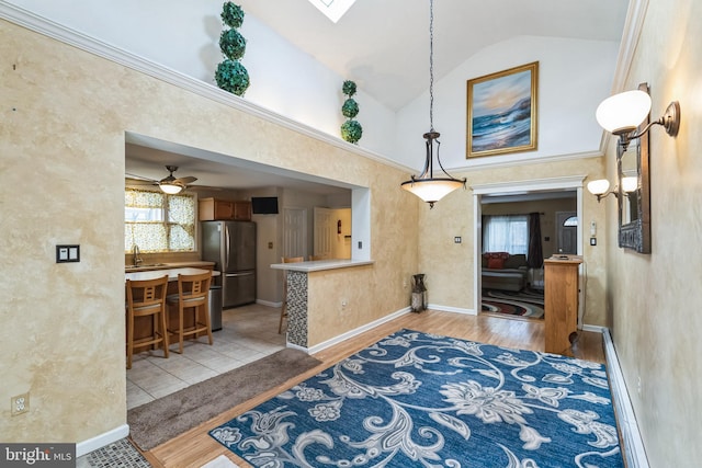 interior space with ceiling fan, high vaulted ceiling, sink, and light hardwood / wood-style flooring