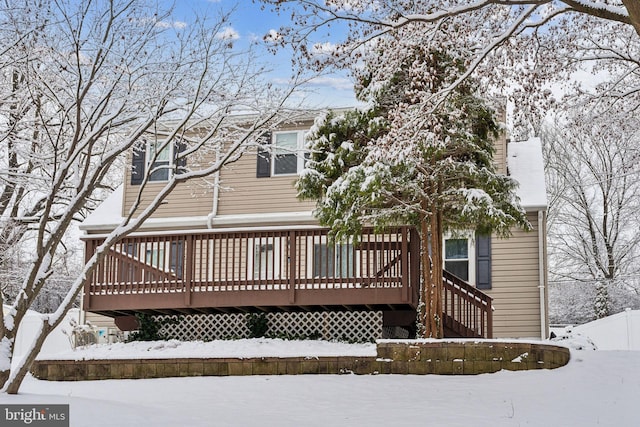 snow covered back of property with a wooden deck