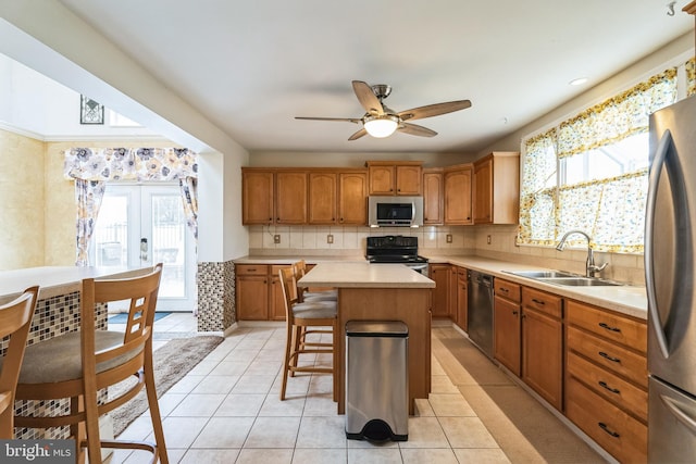 kitchen featuring appliances with stainless steel finishes, sink, a kitchen bar, a center island, and french doors