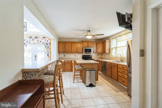 kitchen with a kitchen island, sink, a kitchen breakfast bar, decorative backsplash, and stainless steel appliances