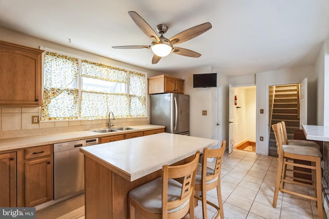 kitchen featuring stainless steel appliances, sink, a kitchen island, and backsplash