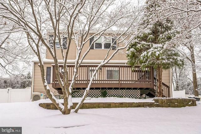 snow covered back of property with a wooden deck