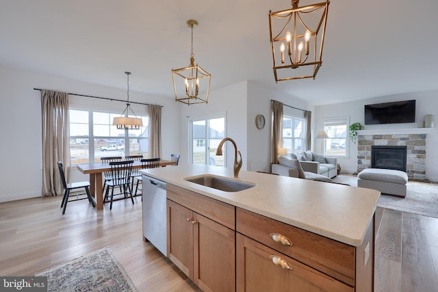 kitchen featuring a center island with sink, light countertops, open floor plan, a sink, and dishwasher