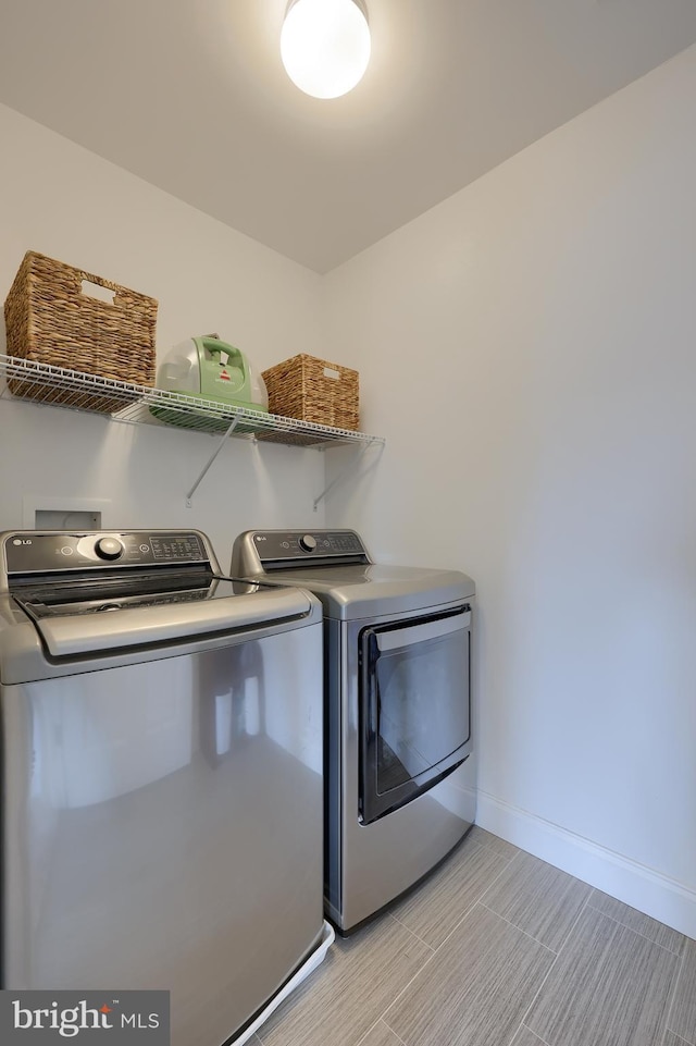 laundry area with laundry area, washer and clothes dryer, and baseboards