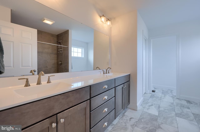 full bathroom featuring double vanity, marble finish floor, a tile shower, and a sink