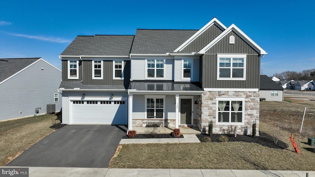 craftsman house featuring aphalt driveway, an attached garage, central air condition unit, stone siding, and board and batten siding