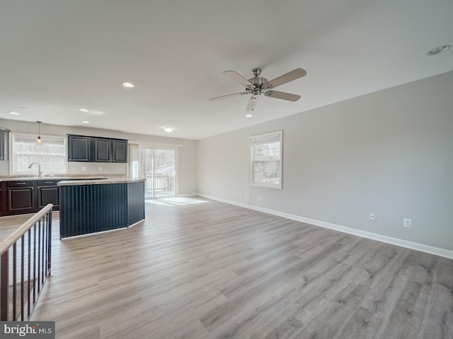 unfurnished living room with light wood-type flooring, a healthy amount of sunlight, and baseboards