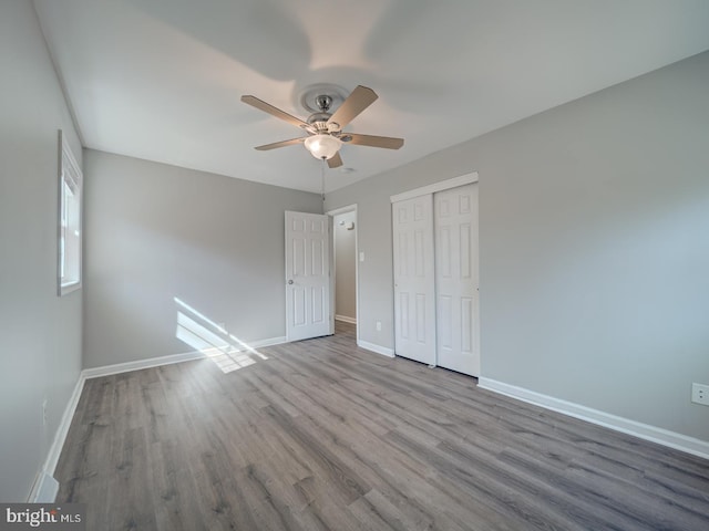 unfurnished bedroom featuring light wood-style floors, a closet, a ceiling fan, and baseboards