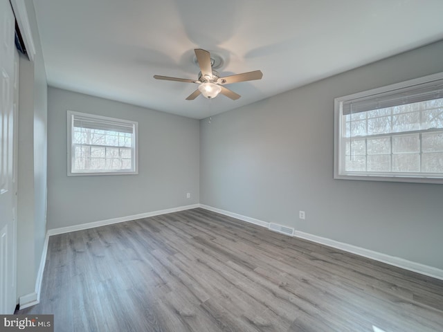 spare room with visible vents, ceiling fan, light wood-style flooring, and baseboards