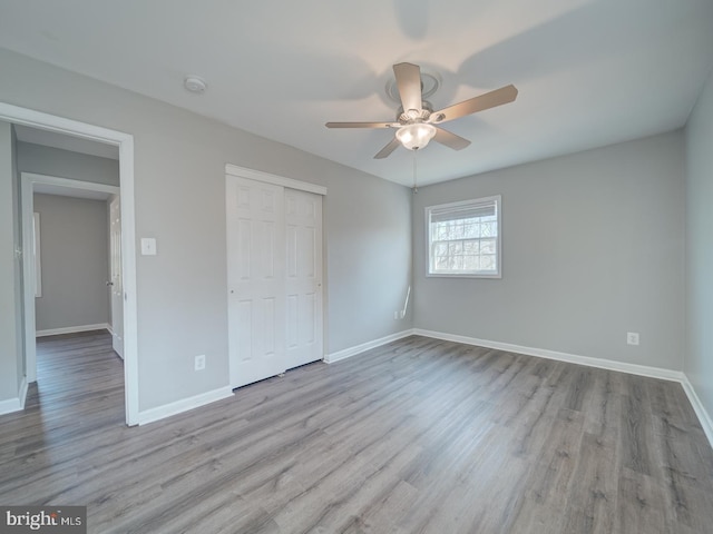 unfurnished bedroom with baseboards, ceiling fan, a closet, and light wood-style floors