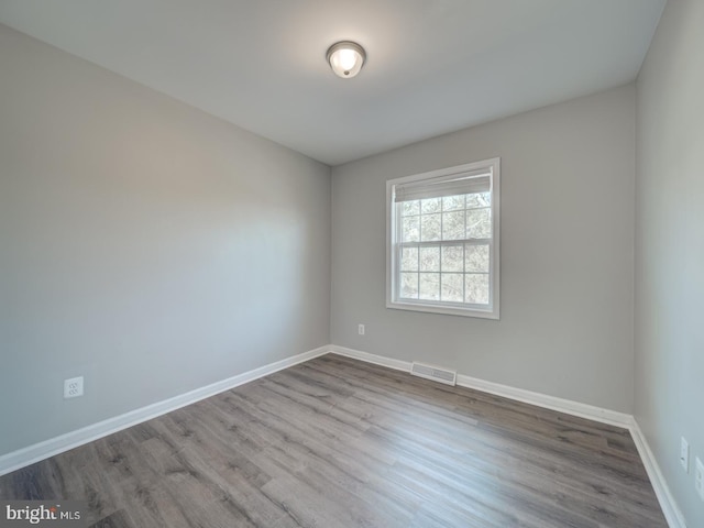 empty room with visible vents, light wood-style flooring, and baseboards