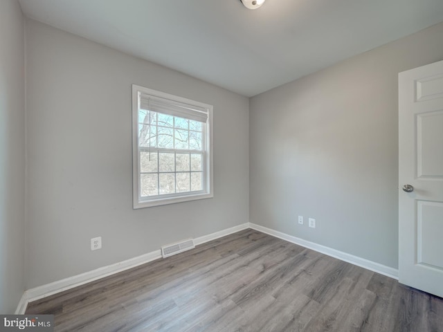 empty room with light wood-style floors, visible vents, and baseboards