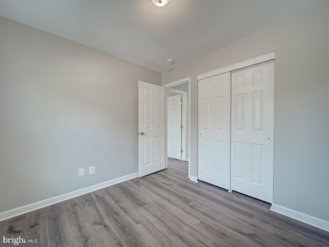 unfurnished bedroom with a closet, light wood finished floors, and baseboards