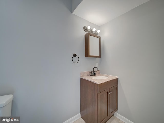 bathroom with toilet, vanity, and baseboards