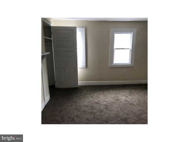 unfurnished room featuring dark carpet