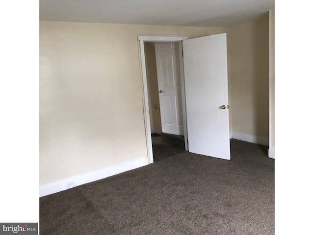 unfurnished room featuring dark carpet