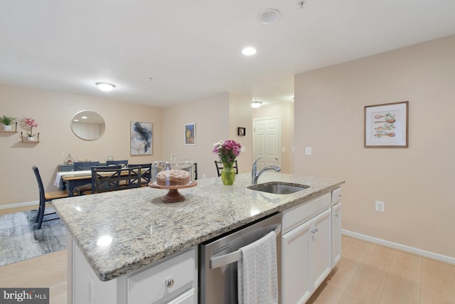 kitchen featuring sink, a kitchen island with sink, light stone countertops, white cabinets, and stainless steel dishwasher