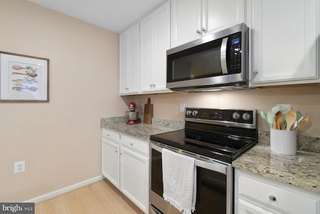 kitchen featuring white cabinetry, light wood-type flooring, light stone countertops, and appliances with stainless steel finishes