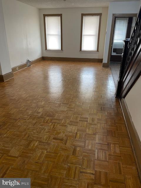 empty room featuring plenty of natural light, dark parquet floors, and a textured ceiling