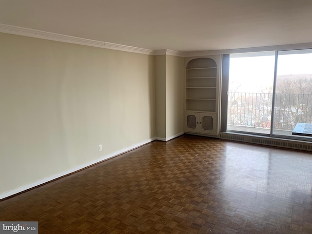 empty room featuring baseboards, built in features, and crown molding