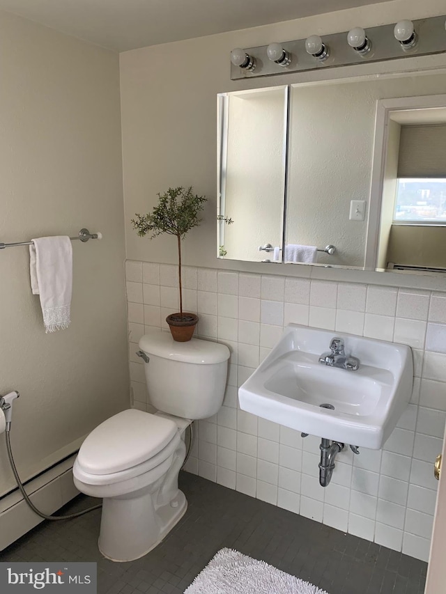 bathroom featuring a baseboard radiator, a sink, tile walls, and toilet