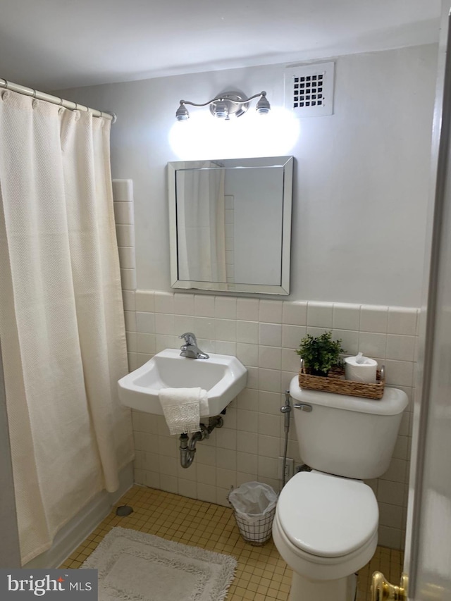 full bathroom featuring visible vents, wainscoting, toilet, tile patterned flooring, and tile walls