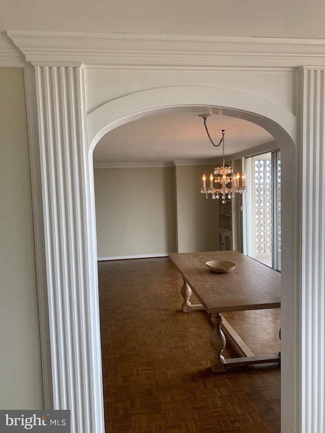 unfurnished dining area featuring ornamental molding, arched walkways, and a notable chandelier