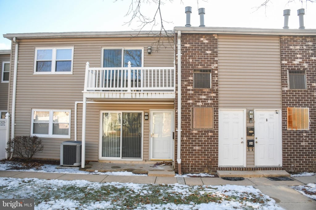 snow covered property featuring central AC and a balcony