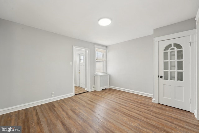 unfurnished room featuring hardwood / wood-style floors and radiator heating unit