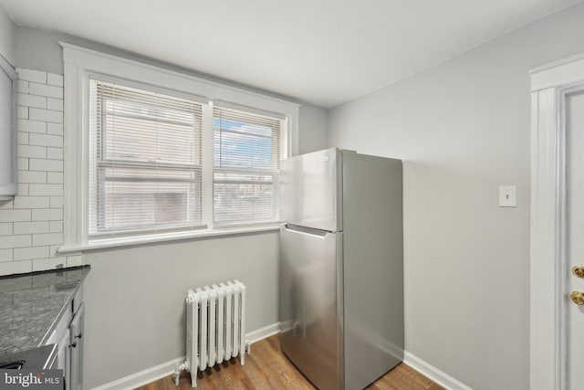 kitchen with stainless steel fridge, radiator, and light hardwood / wood-style flooring