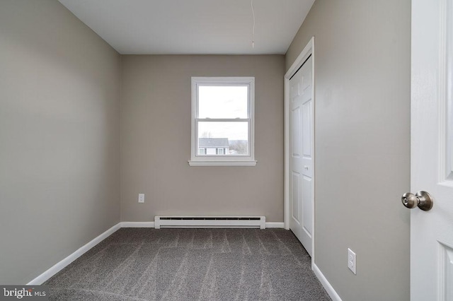 unfurnished bedroom with a baseboard heating unit, a closet, and dark colored carpet