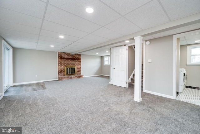 basement featuring a fireplace, carpet flooring, washer and clothes dryer, and a paneled ceiling