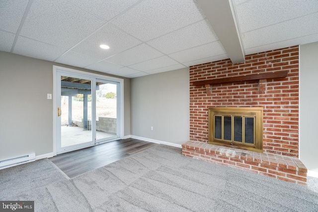 unfurnished living room with baseboard heating, a paneled ceiling, a fireplace, and hardwood / wood-style flooring