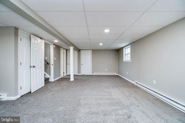 basement with a drop ceiling, a baseboard radiator, and carpet