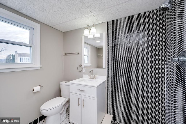 bathroom with vanity, toilet, a drop ceiling, and a shower