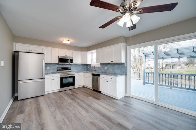 kitchen featuring sink, light hardwood / wood-style flooring, white cabinetry, stainless steel appliances, and tasteful backsplash