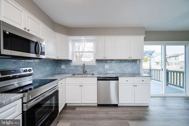 kitchen with appliances with stainless steel finishes, light stone countertops, sink, and white cabinets