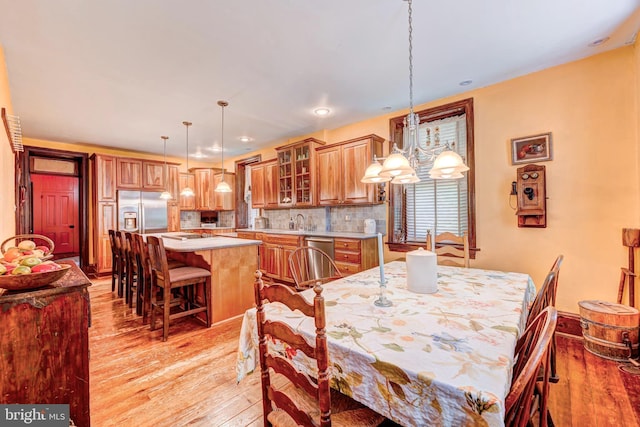 dining space with a chandelier, sink, and light hardwood / wood-style flooring