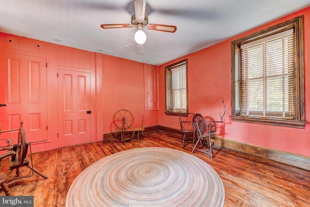 living area with wood-type flooring and ceiling fan