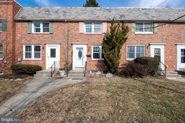 townhome / multi-family property with a front yard, a high end roof, and brick siding