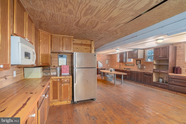 kitchen with light hardwood / wood-style flooring, stainless steel fridge, wooden ceiling, and wood walls