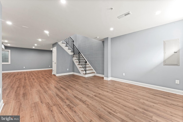 unfurnished living room featuring electric panel and light hardwood / wood-style floors