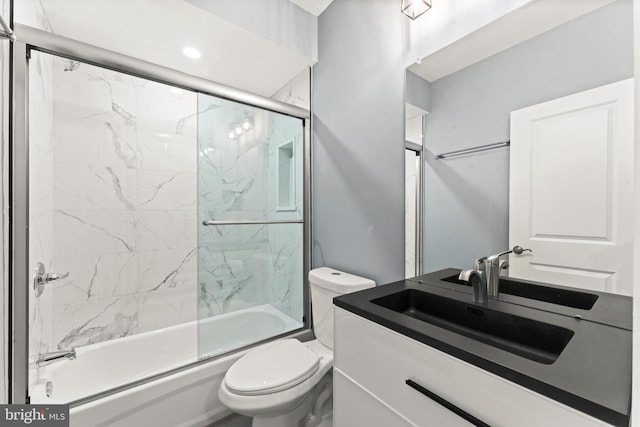 full bathroom featuring vanity, combined bath / shower with glass door, and toilet