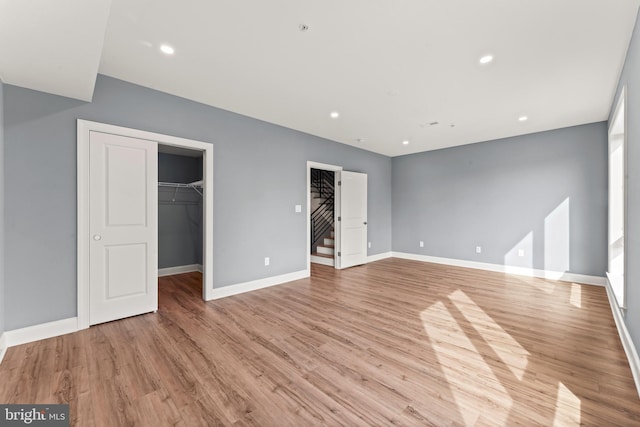 unfurnished bedroom featuring a spacious closet, light hardwood / wood-style flooring, and a closet