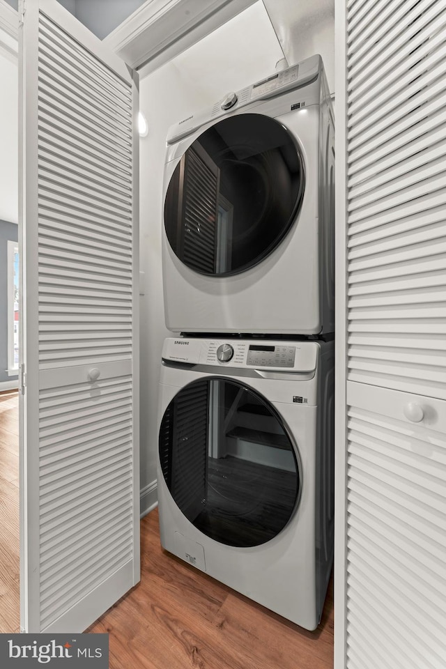 laundry room featuring stacked washer and dryer and hardwood / wood-style flooring