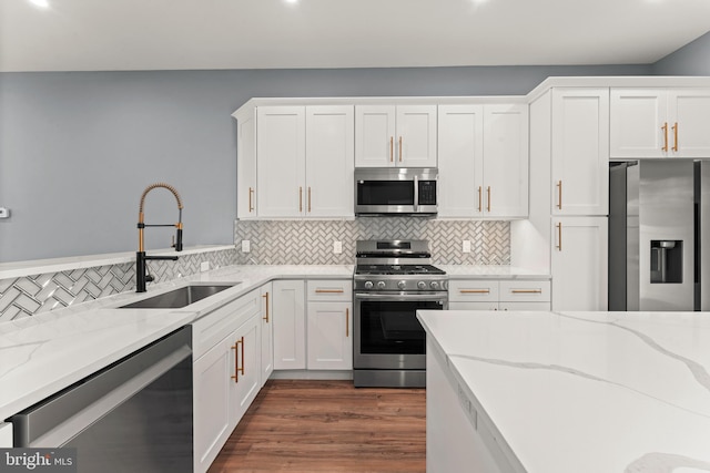 kitchen featuring stainless steel appliances, white cabinetry, sink, and light stone counters