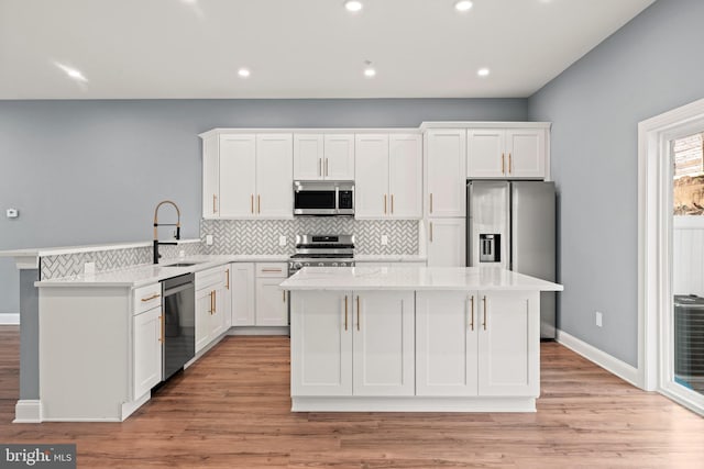 kitchen with sink, white cabinets, backsplash, a center island, and stainless steel appliances